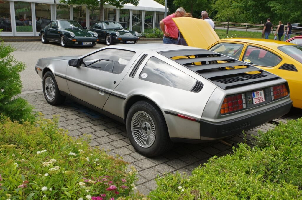 A silver DeLorean DMC-12 car with its gull-wing door open