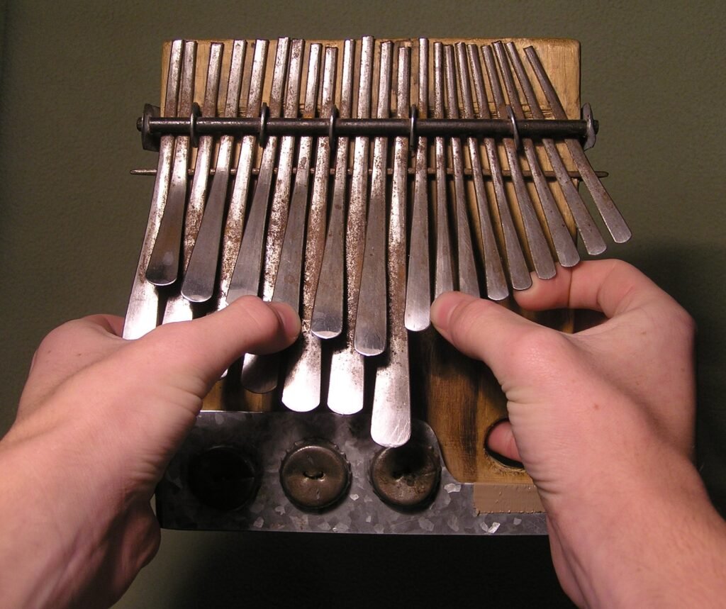 Hands plucking the metal tines of an mbira, a kalimba-style lamellophone