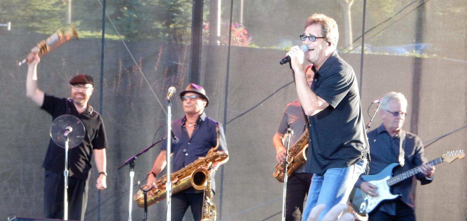 Huey Lewis performing on stage with a microphone in 2016