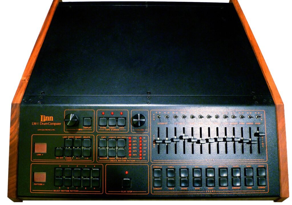 Front panel of a Linn LM-1 Drum Computer with a row of mixer faders and drum buttons in a wooden case