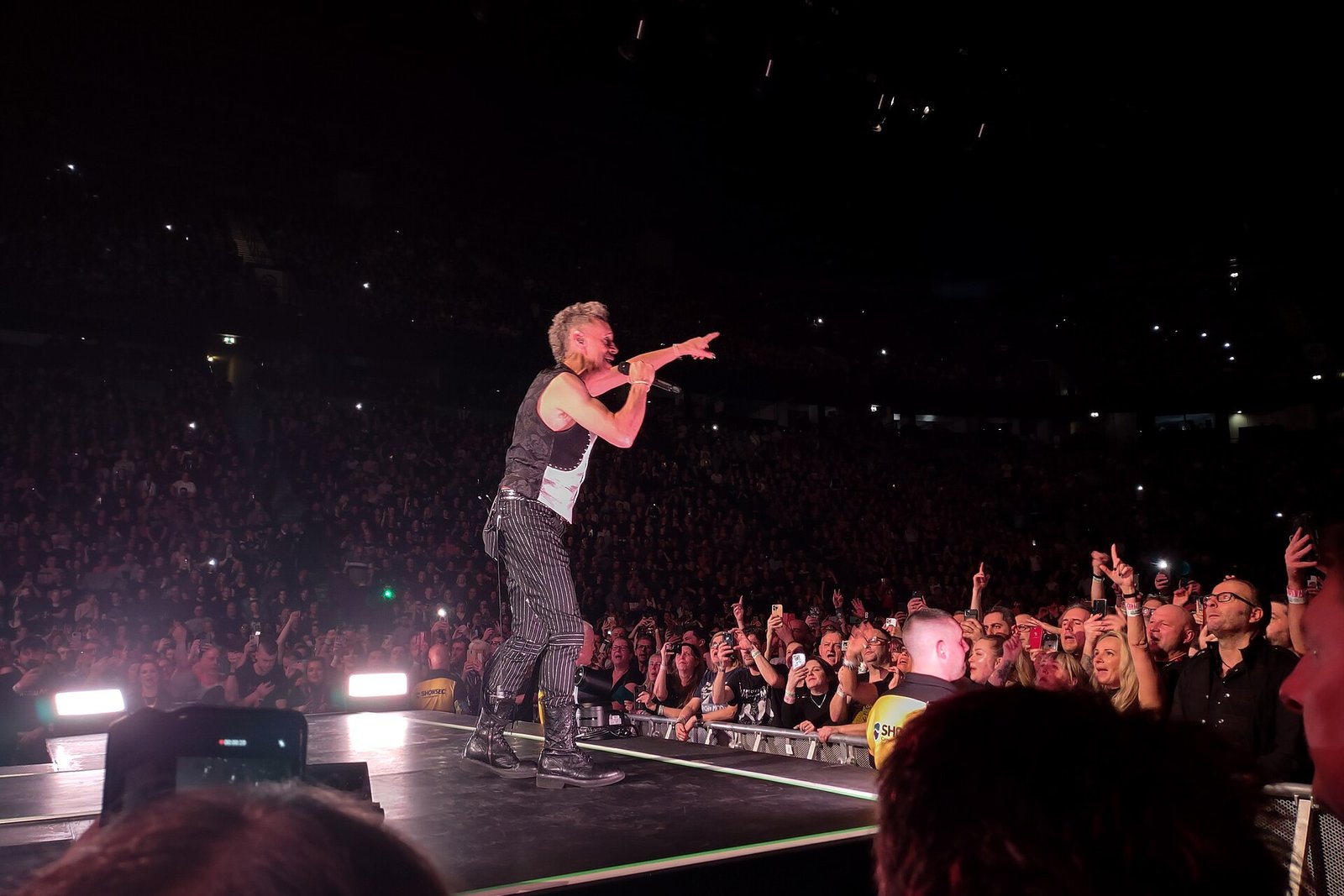 Martin Gore of Depeche Mode singing and pointing at the crowd from the edge of the stage at Manchester Arena
