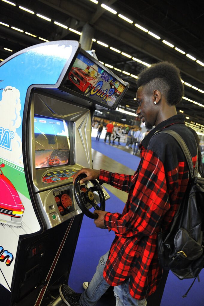 Visitor playing an upright Sega Out Run arcade cabinet at Japan Expo