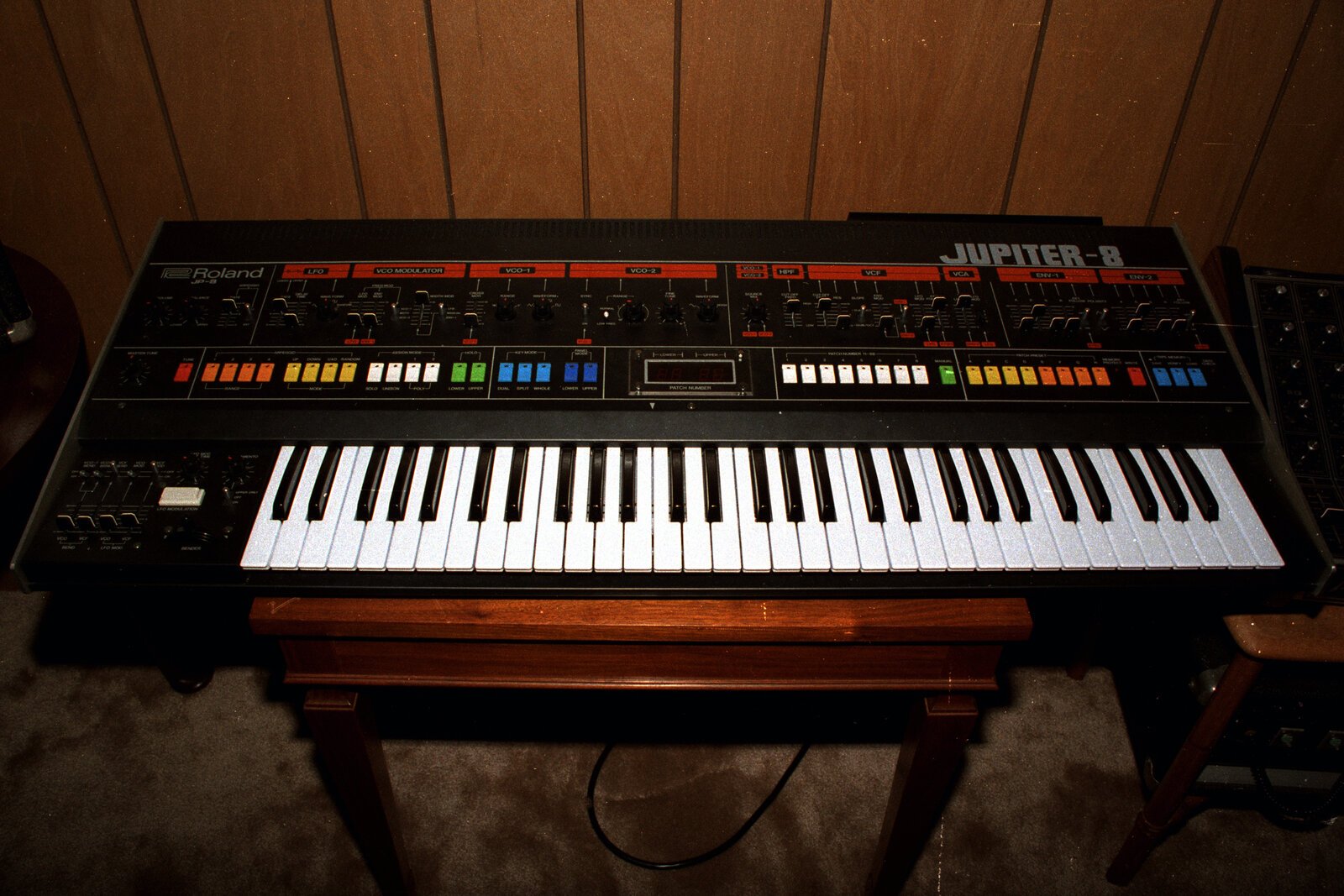 Roland Jupiter-8 synthesizer front panel with coloured sliders and 61-key keyboard