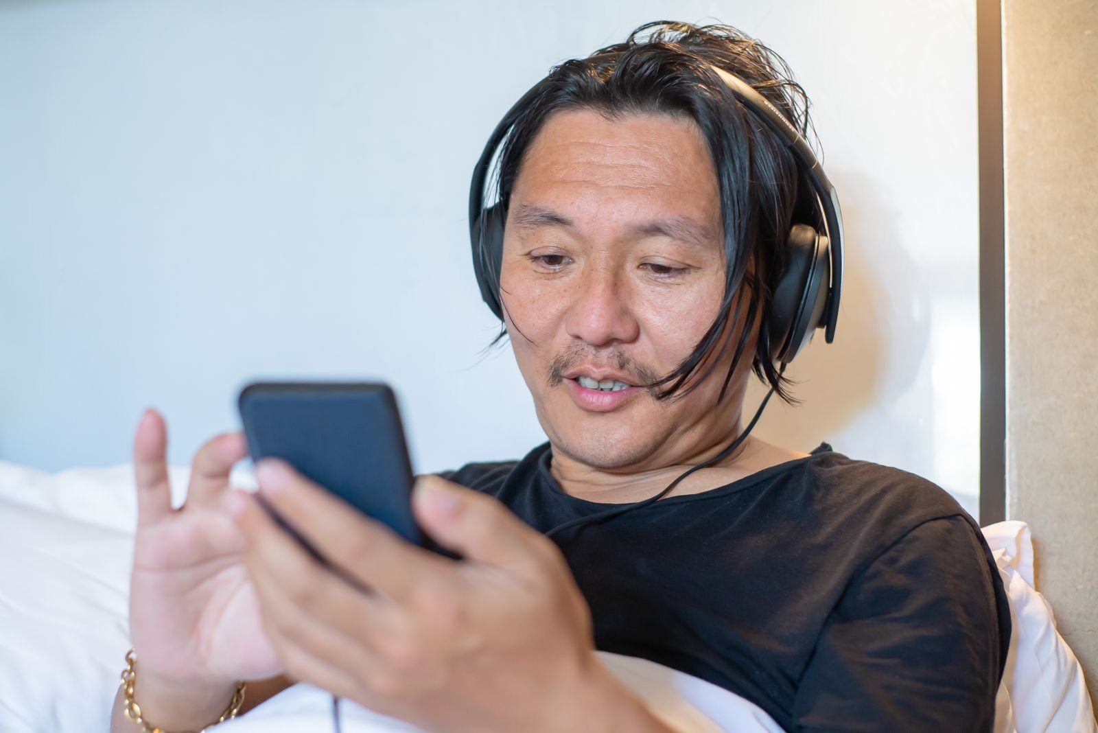 Man wearing headphones while checking a music streaming app on his smartphone