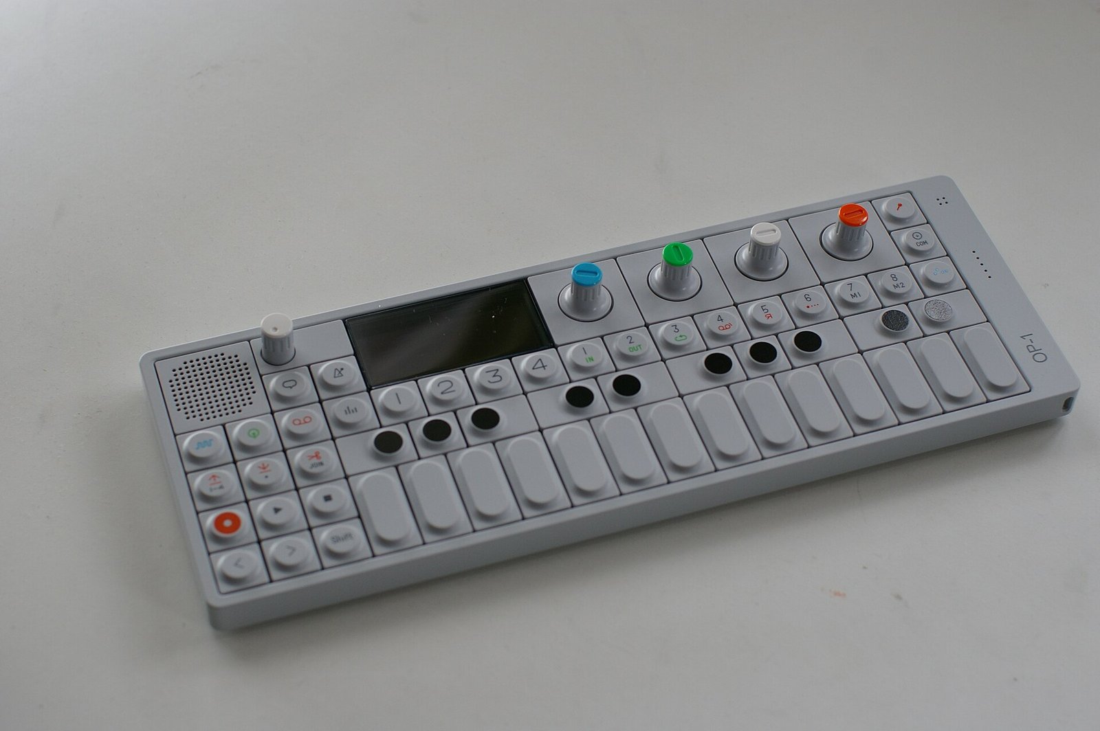A white Teenage Engineering OP-1 portable synthesizer with coloured knobs, photographed in June 2011