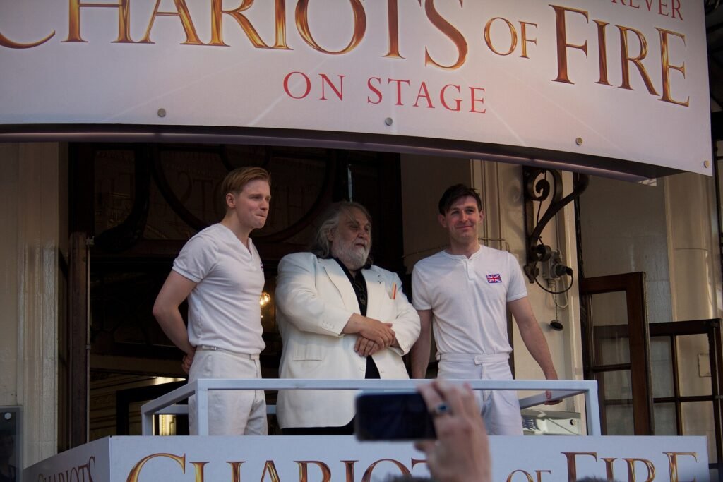 Vangelis with actors Jack Lowden and James McArdle on a balcony at the Gielgud Theatre in London